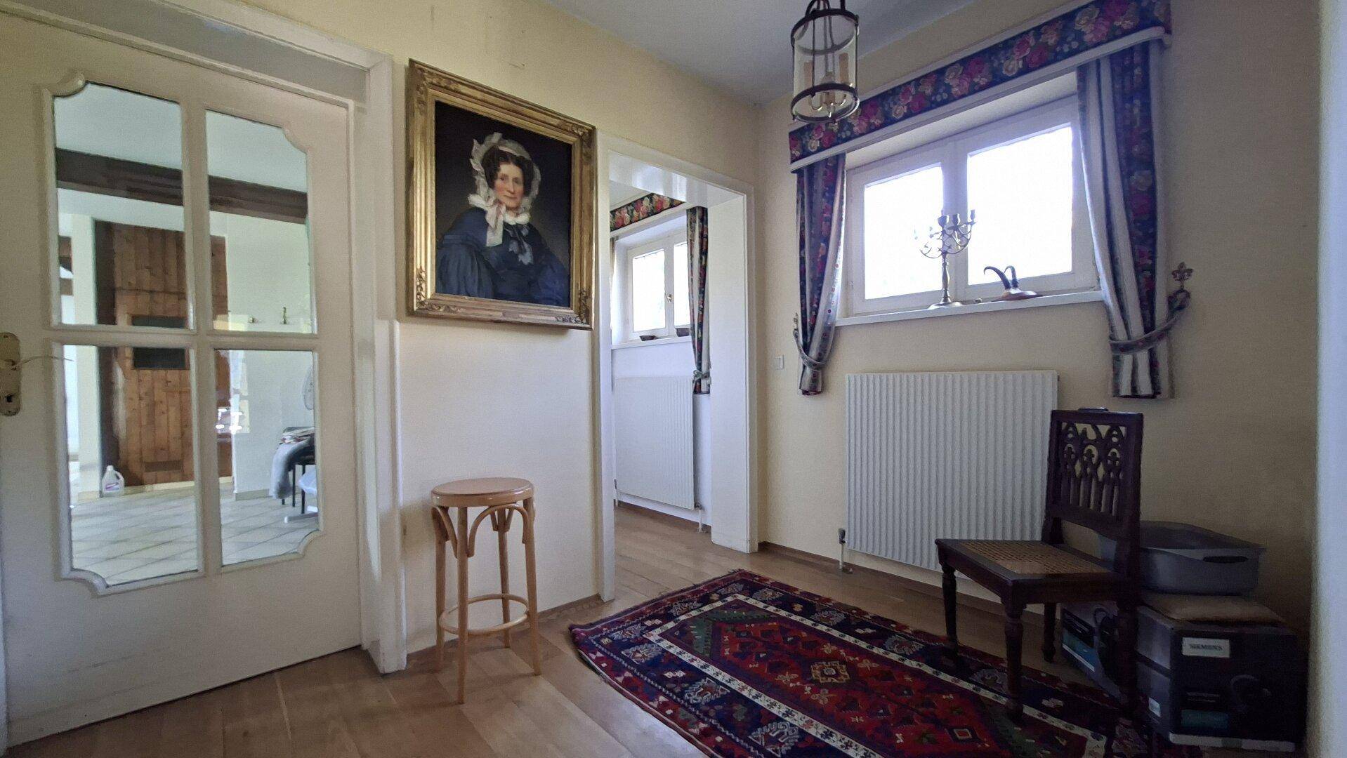 Heller Flur mit Holzboden, einem Gemälde und einem Fenster, das Tageslicht hereinlässt.
