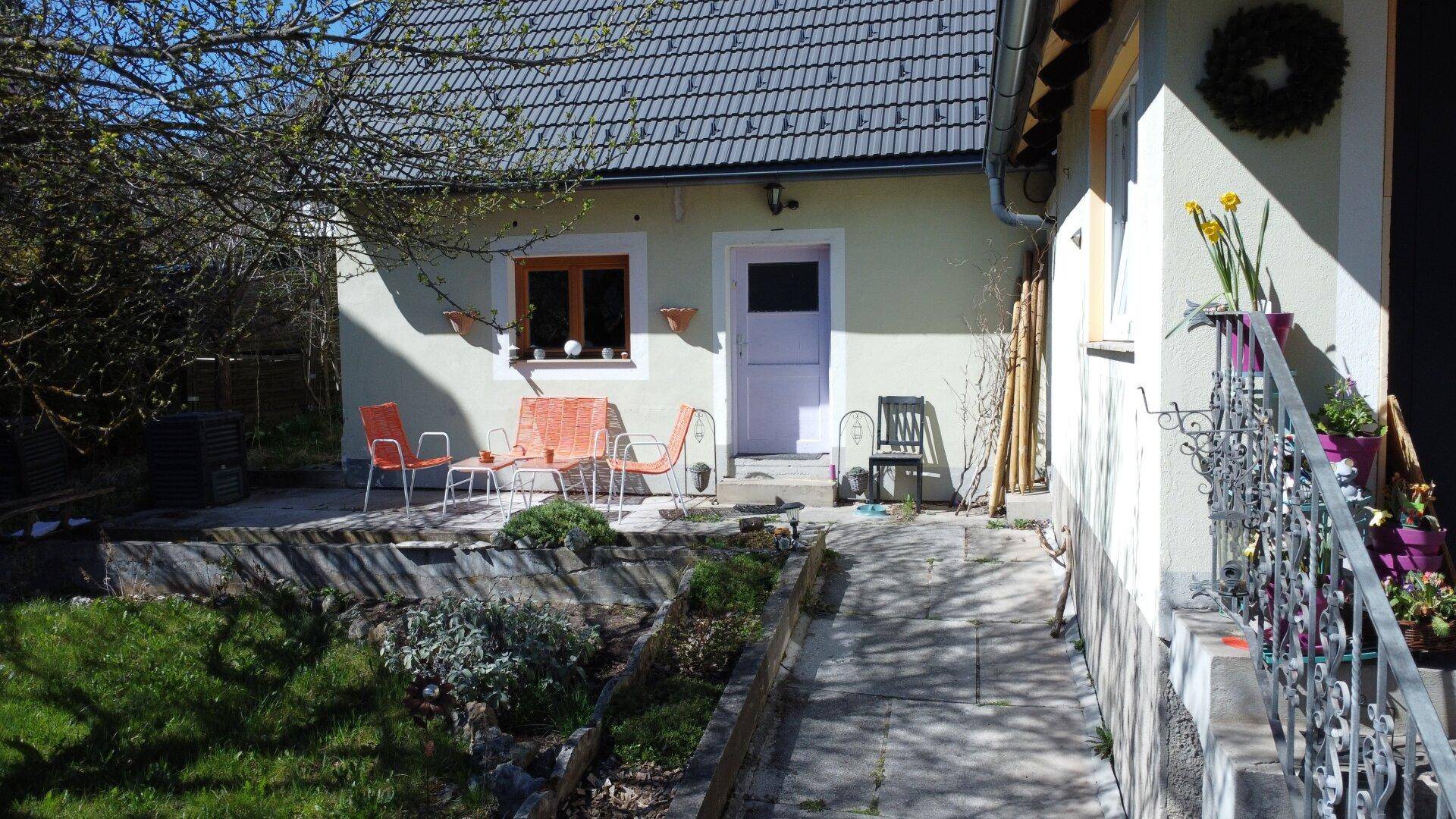Sonniger Außenbereich mit Terrasse, Gartenmöbeln und einer Rampe für barrierefreien Zugang.