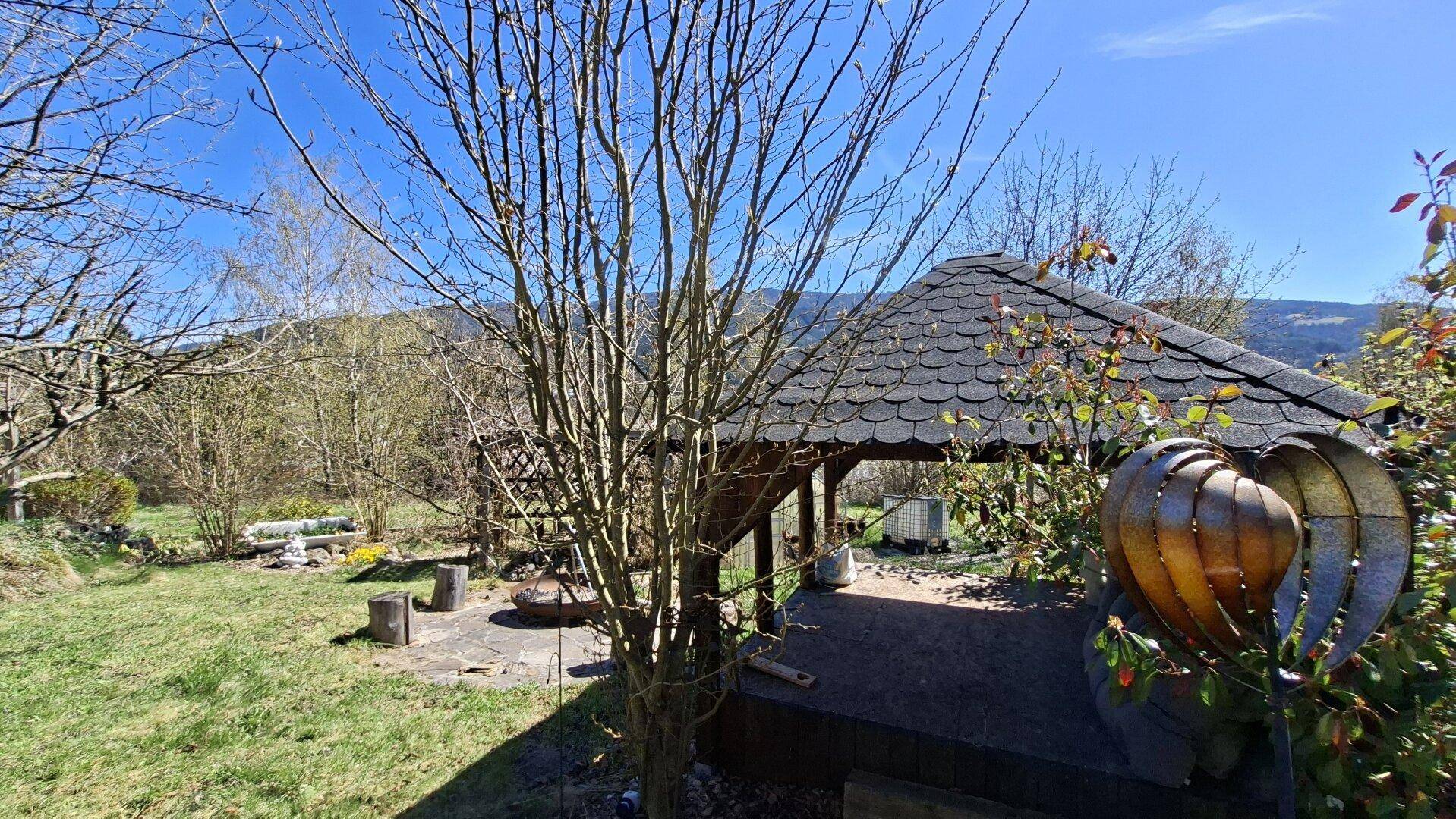 Gartenbereich mit einem Holzpavillon und Blick auf die umliegende Landschaft.