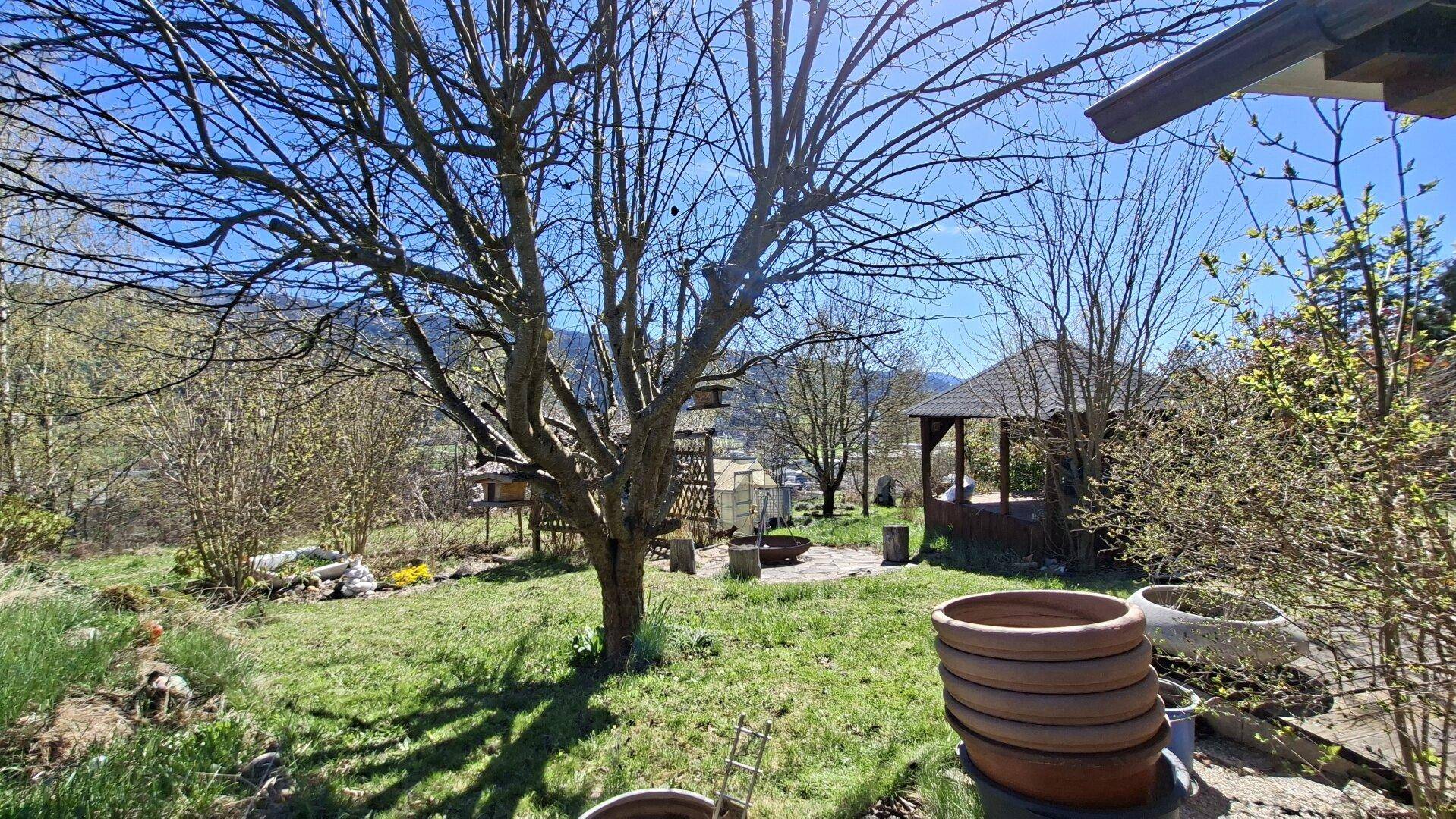 Großer Garten mit Bäumen, einem Pavillon und Blick auf die Umgebung.
