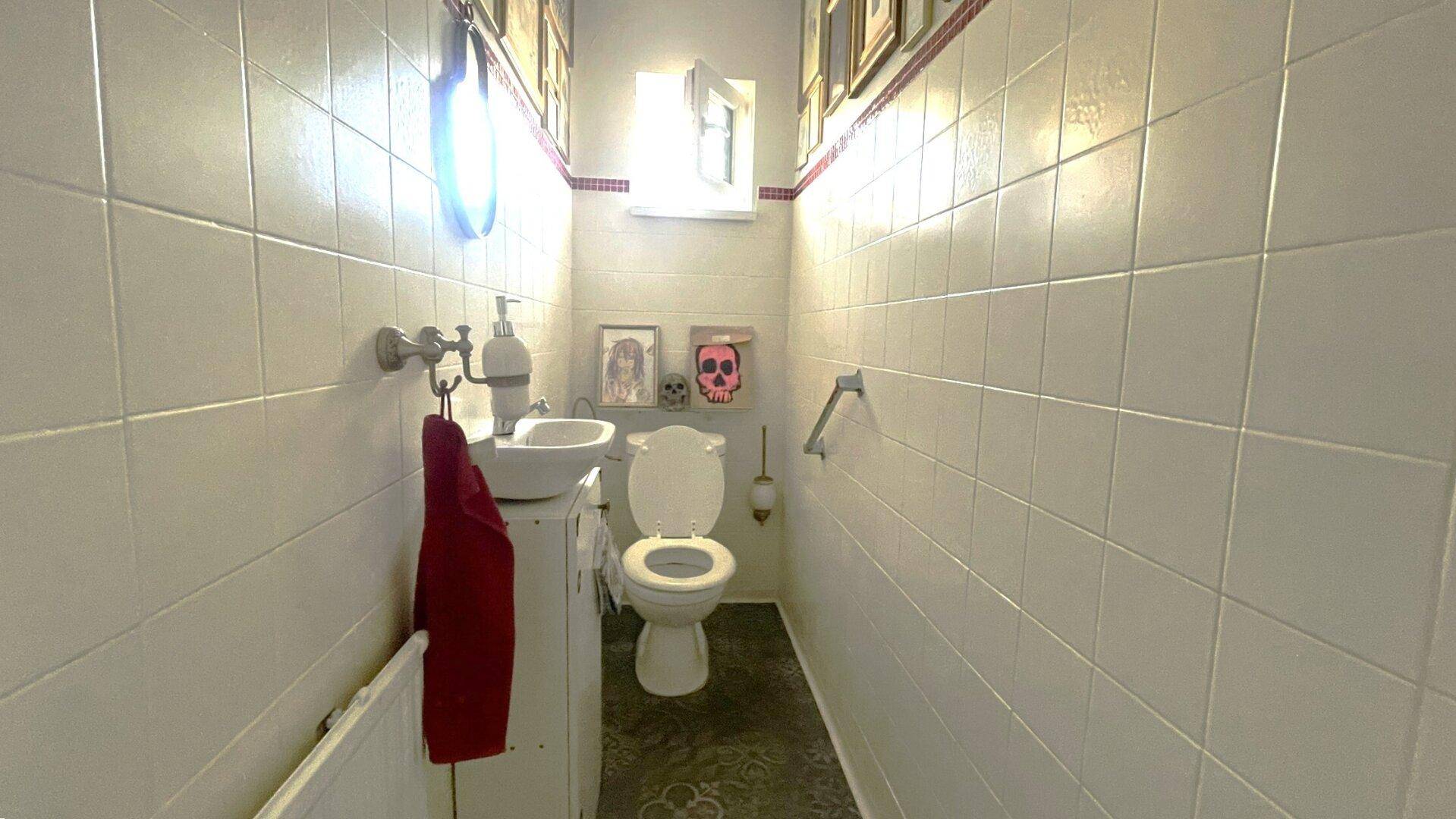 Kleines WC mit weißen Fliesen, Toilette und Waschbecken.