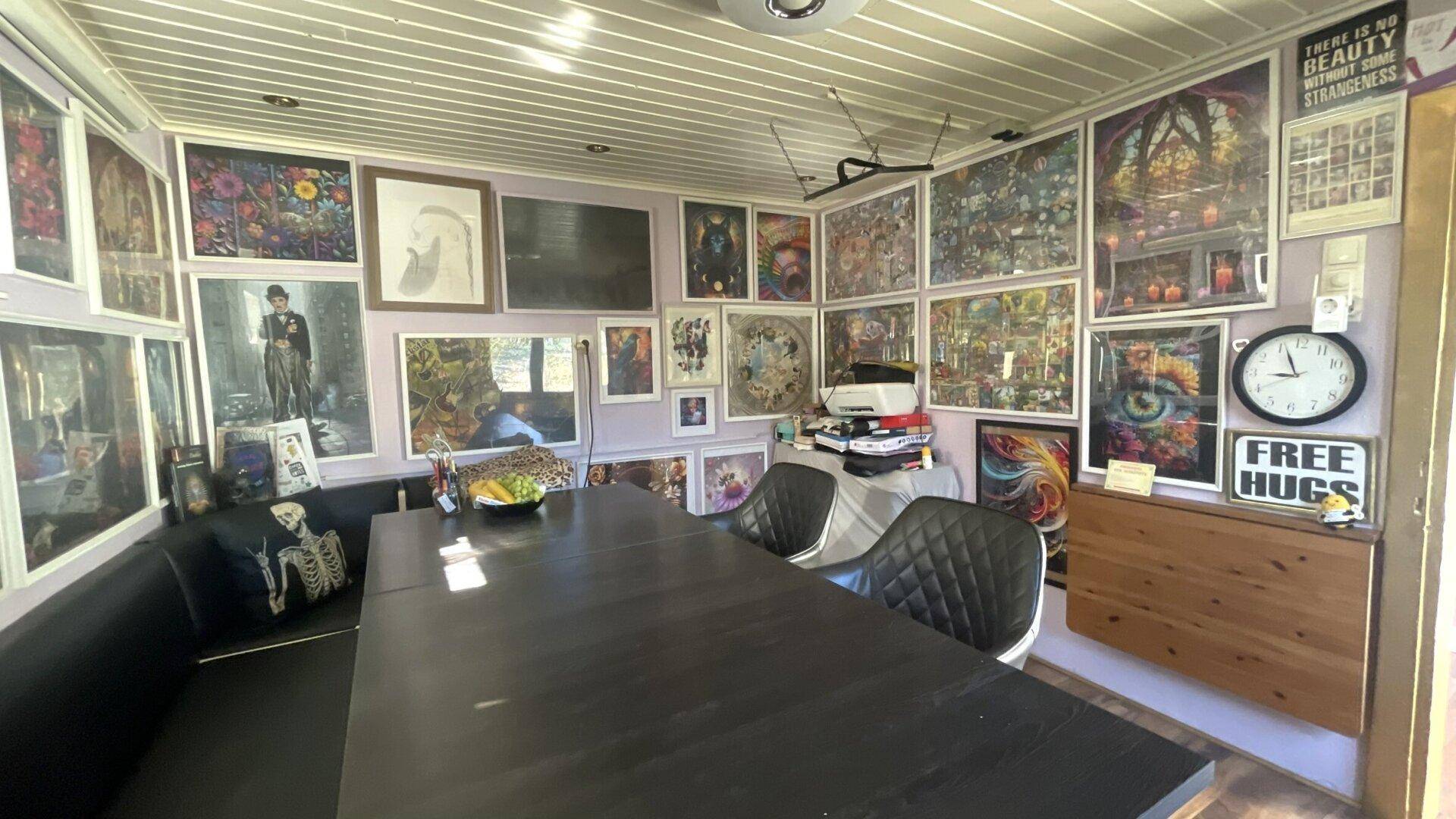 Esszimmer mit großem Tisch, Eckbank und Wänden voller bunter Kunstwerke und Dekorationen.