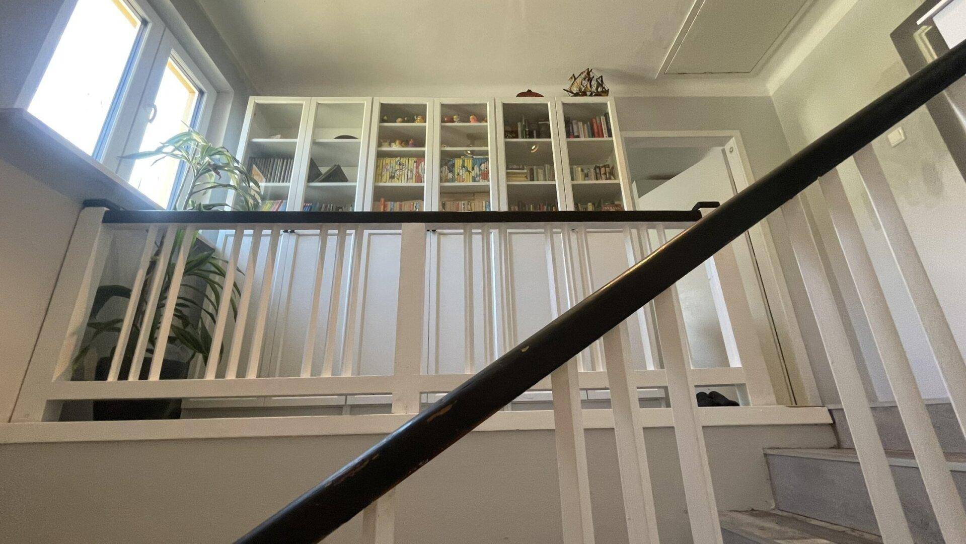 Treppenabsatz mit eingebauten Bücherregalen und Blick auf das obere Stockwerk.