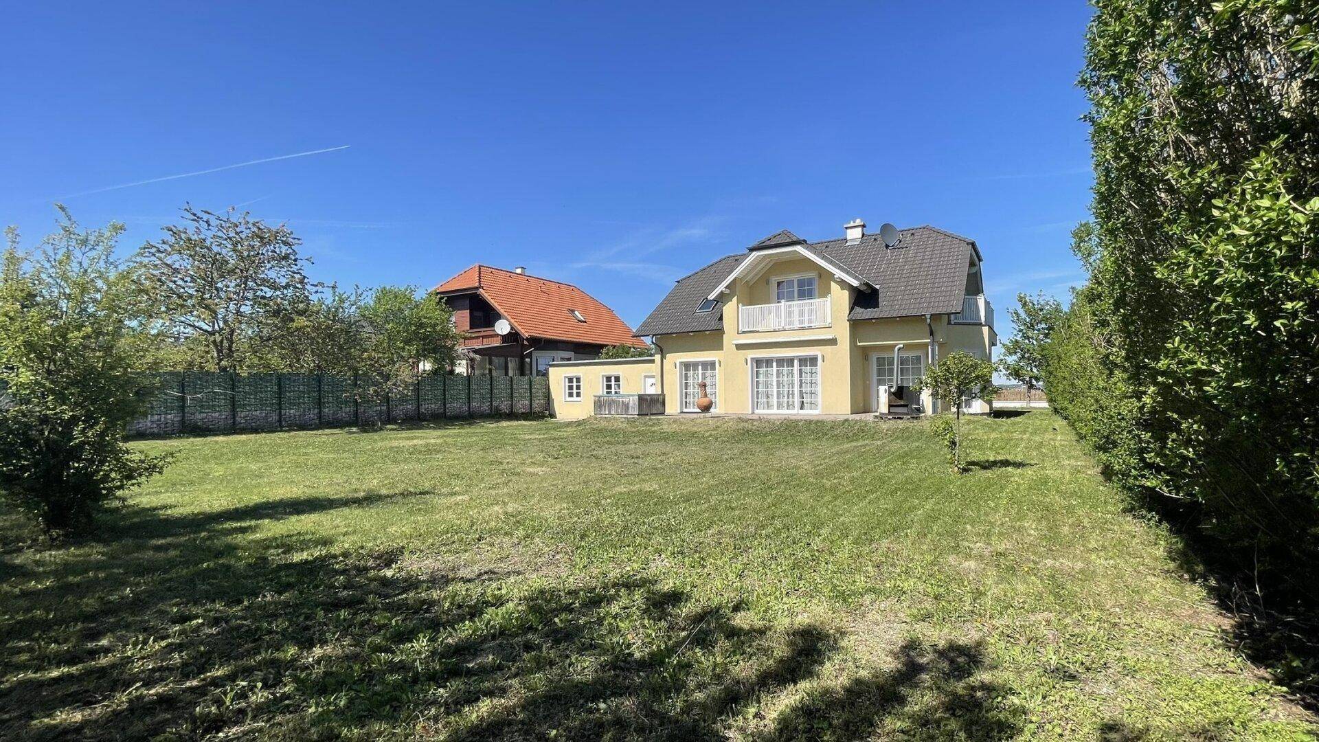 Weitläufiger Gartenbereich mit großem Rasen und dem Einfamilienhaus im Hintergrund.