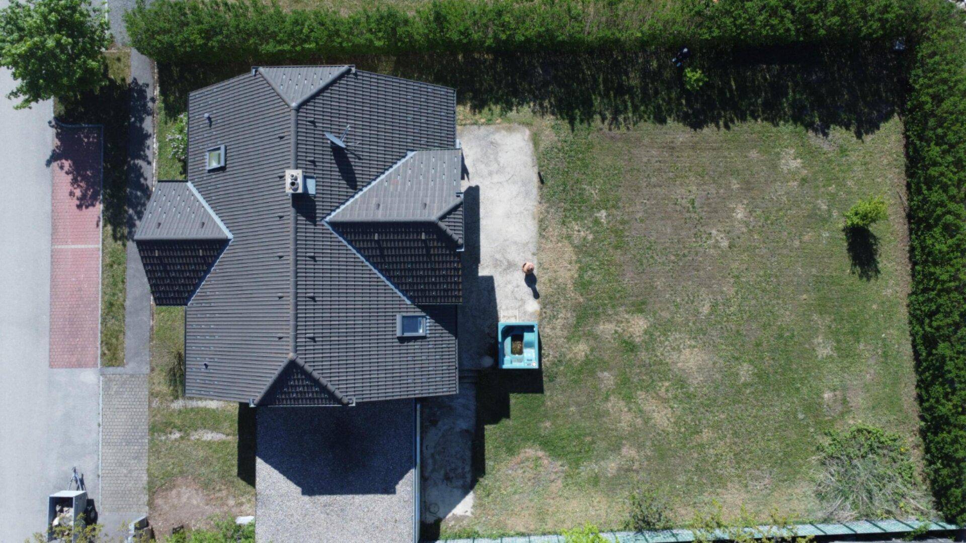 Luftaufnahme eines modernen Einfamilienhauses mit großem Garten und gepflegter Rasenfläche.