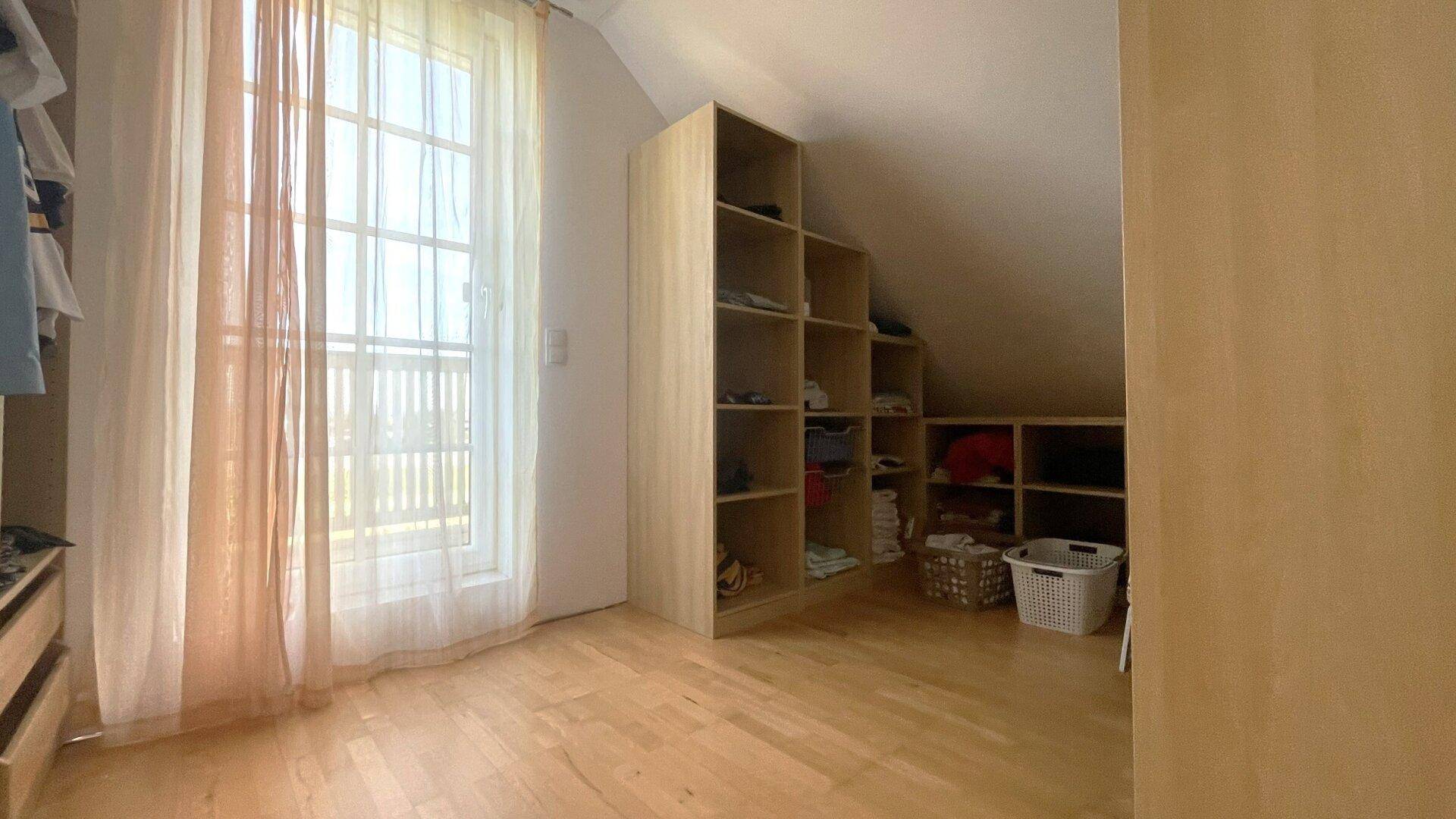Praktischer Abstellraum mit eingebauten Regalen und einem Fenster unter der Dachschräge.