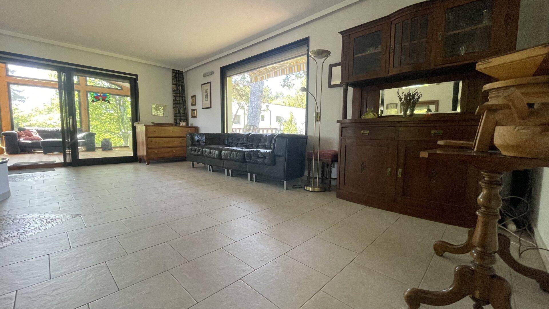 Geräumiges Wohnzimmer mit Fliesenboden, traditionellen Holzmöbeln und Zugang zur Terrasse.