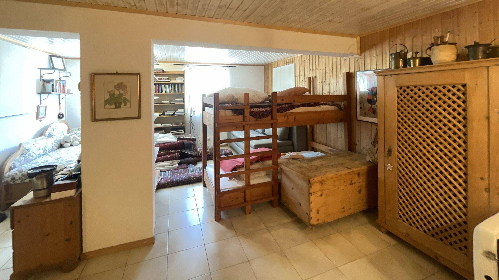 Rustikales Schlafzimmer mit Etagenbett, Holzmöbeln und Fliesenboden.