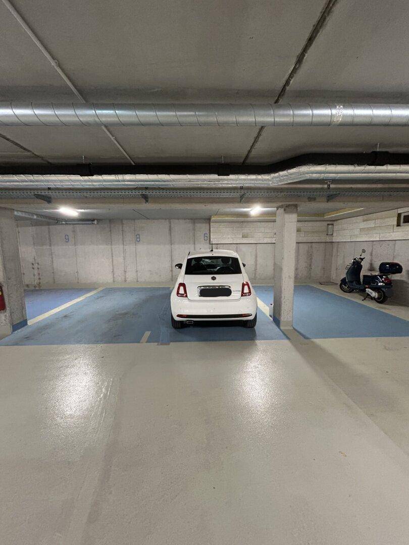 Tiefgarage mit markierten Stellplätzen und einem geparkten Auto, bietet sicheren Parkraum.