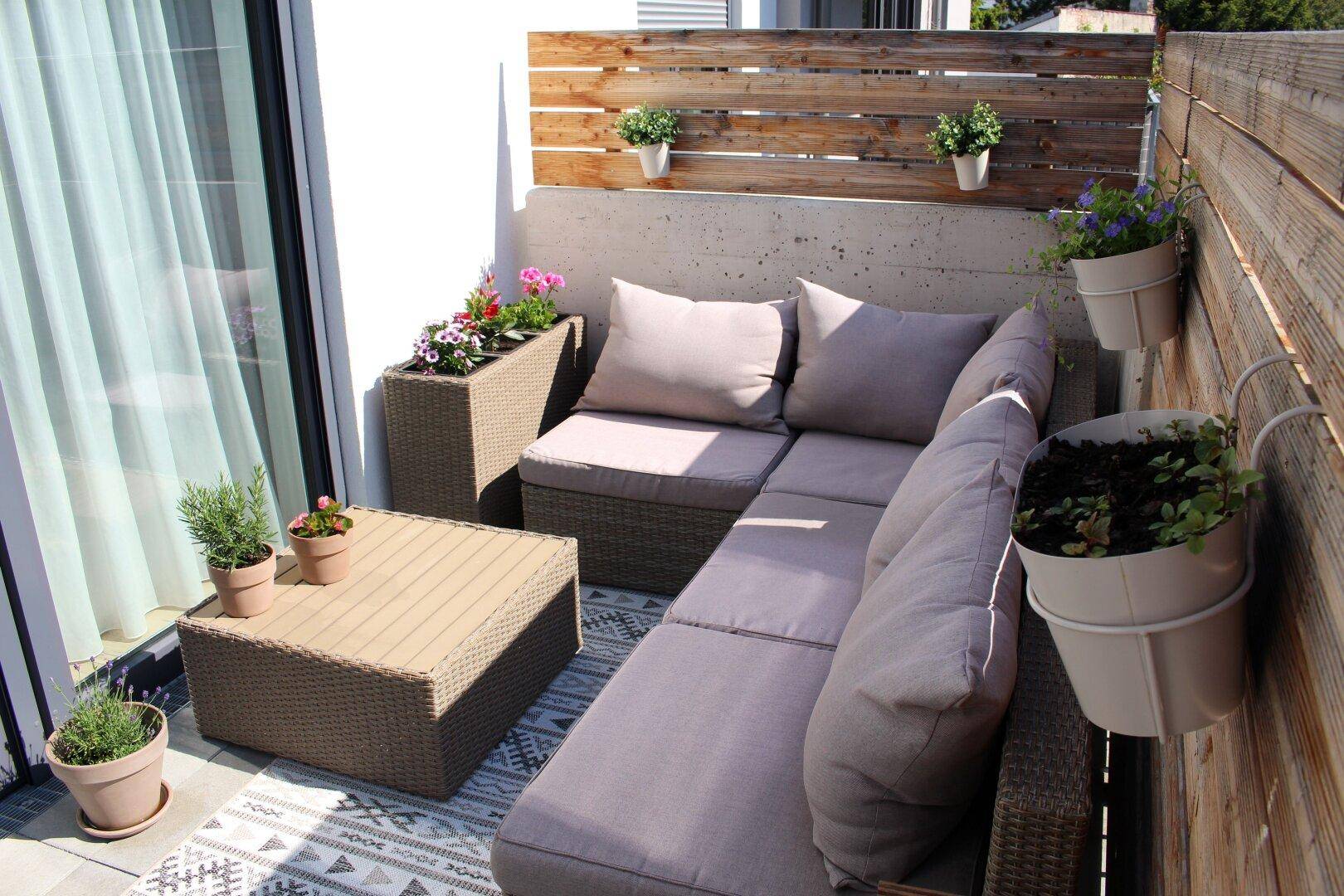 Gemütlicher Balkon mit Lounge-Möbeln, Holzwand und Pflanzen, perfekt für den Außenbereich.