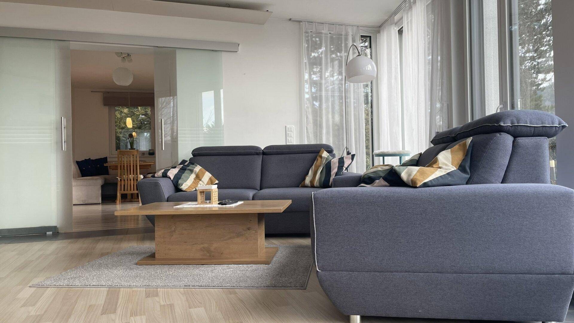 Wohnzimmer mit bequemer Couch, Couchtisch und Schiebetür zum Essbereich.