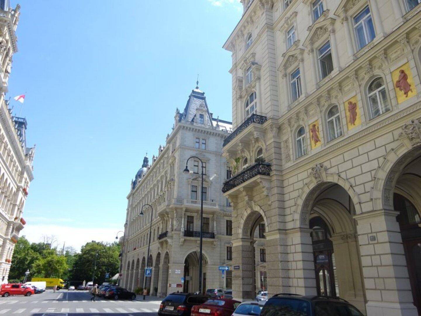 Historische Gebäude entlang einer belebten Straße unter blauem Himmel.