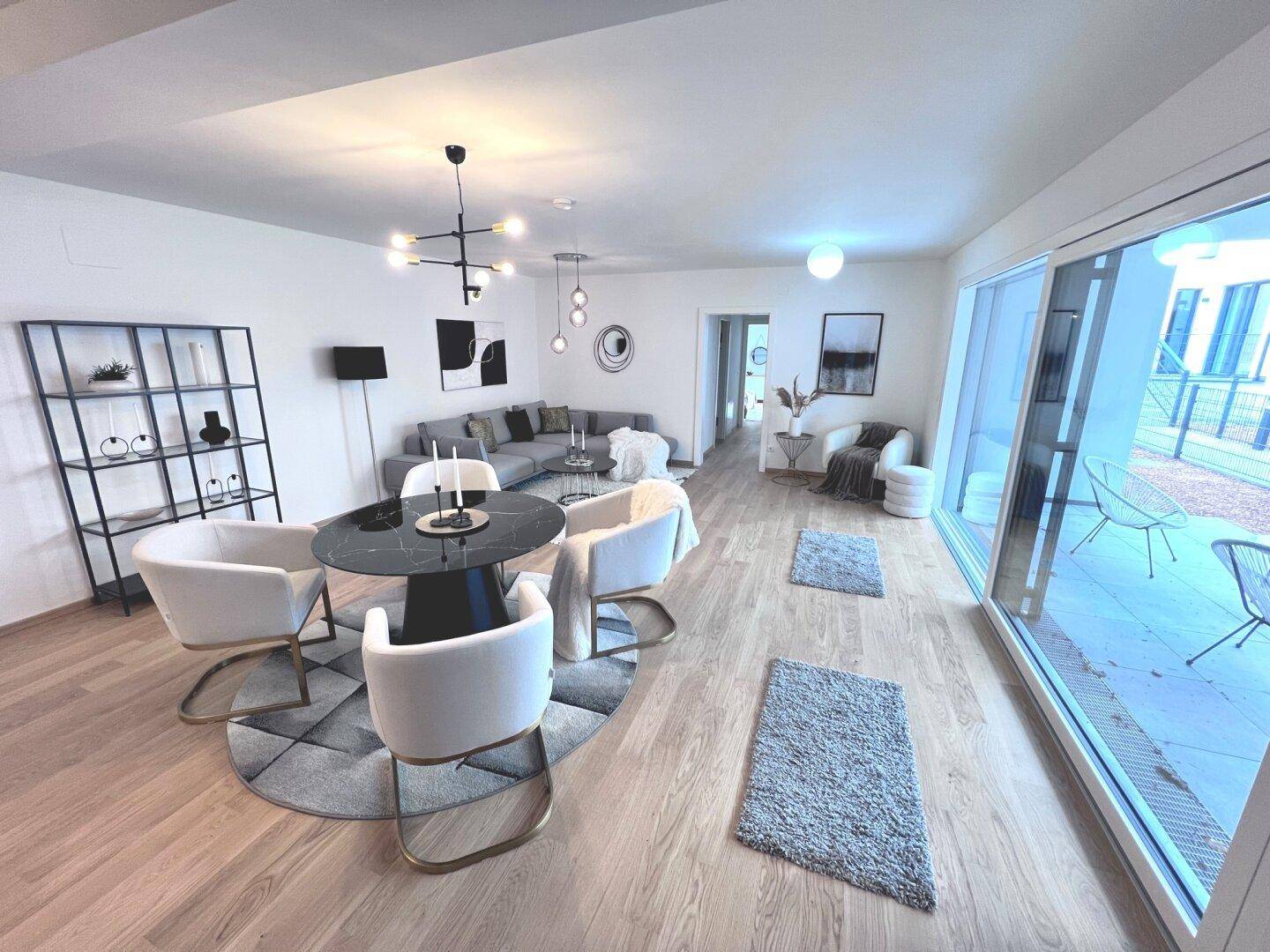 Geräumiger Wohn-Essbereich mit elegantem Esstisch, modernen Möbeln und Zugang zur Terrasse.