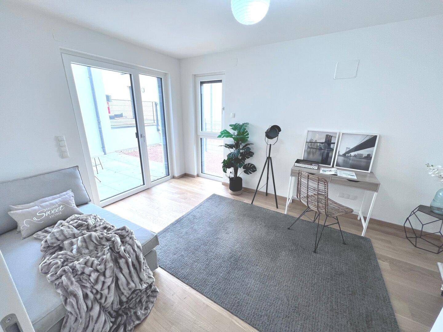 Helles Arbeitszimmer mit Tagesbett, Schreibtisch und großem Fenster mit Zugang zur Terrasse.