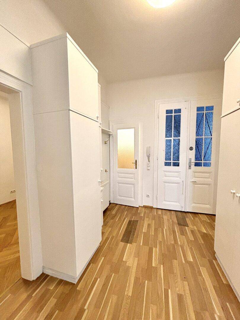 Flur mit Einbauschränken, Parkettboden und Zugang zu weiteren Zimmern.