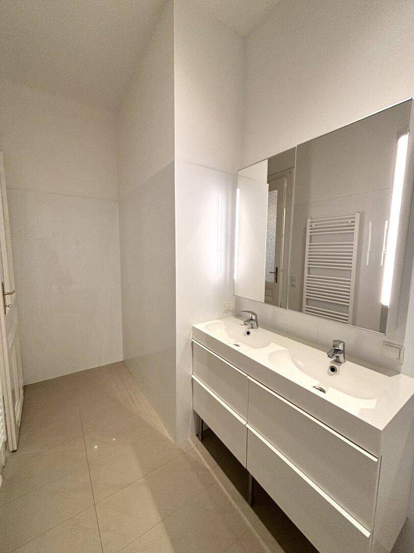 Modernes Badezimmer mit Doppelwaschbecken, großem Spiegel und hellen Fliesen.