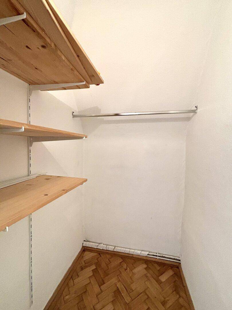 Praktischer Abstellraum mit Holzregalen und Kleiderstange, ideal für zusätzlichen Stauraum.
