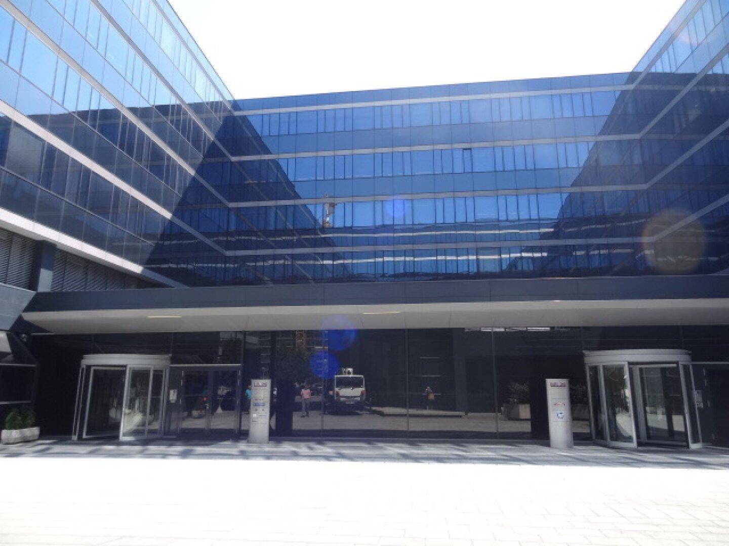 Eingangsbereich eines modernen Bürogebäudes mit großer Glasfront und Drehtüren.
