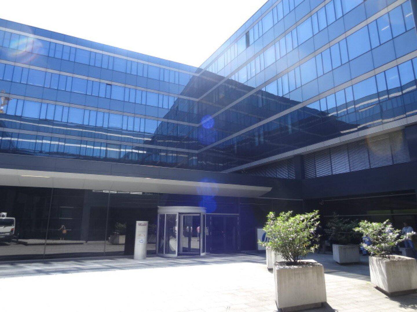 Detailansicht des Haupteingangs mit reflektierender Glasfassade und Drehtür.