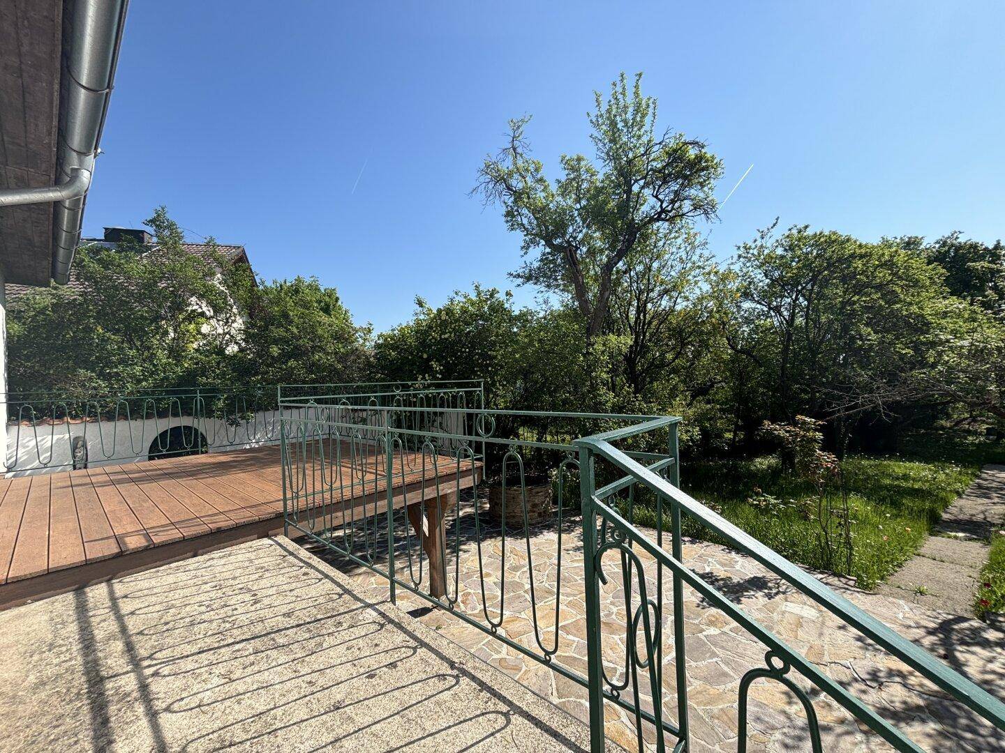 Obere Steinterrasse mit Metallgeländer und Blick auf den weitläufigen Garten.