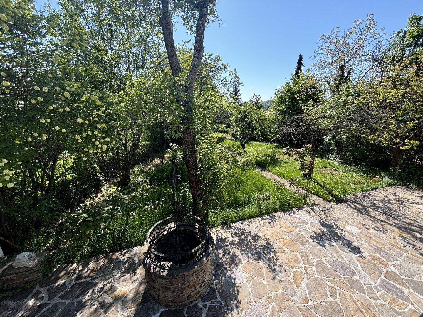 Weitläufiger Gartenbereich mit altem Brunnen und Blick auf die umliegende Natur.