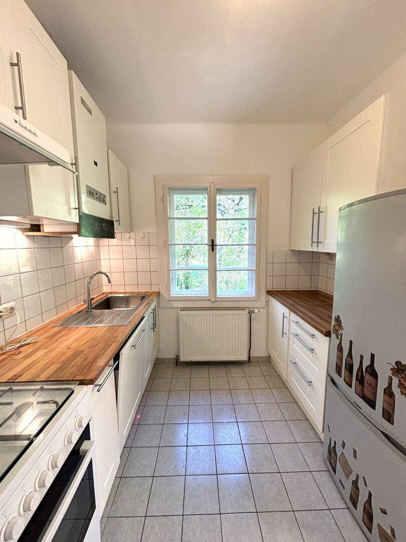 Funktionale Küche mit weißen Schränken, Holz-Arbeitsplatten und Fliesenboden.