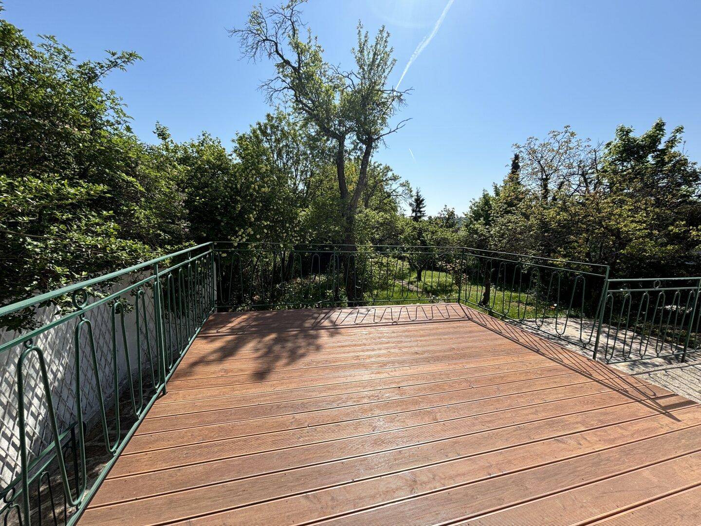 Große Holzterrasse mit Metallgeländer und weitem Blick in die grüne Umgebung.