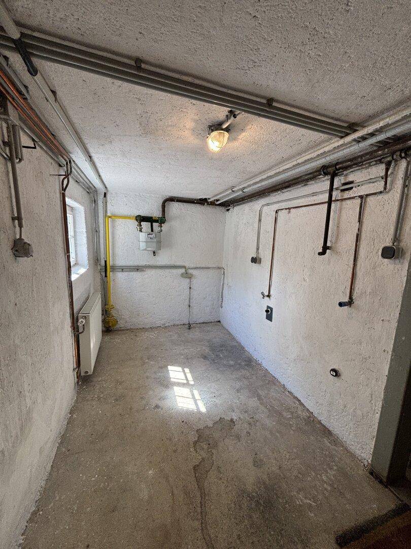 Hauswirtschaftsraum im Keller mit sichtbaren Leitungen und Heizkörper.