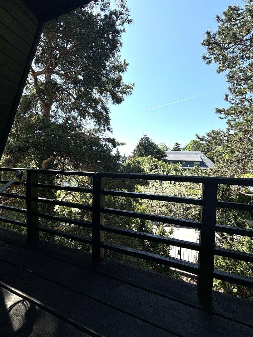 Kleiner Balkon mit schwarzem Geländer und weitem Blick über die Baumwipfel.