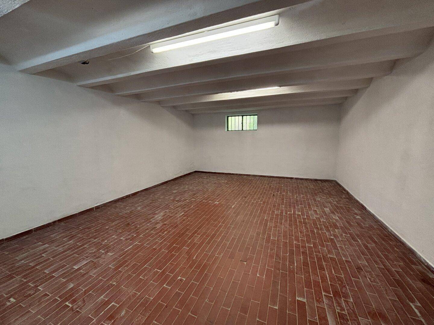 Geräumiger Kellerraum mit Ziegelboden und sichtbaren Deckenbalken.