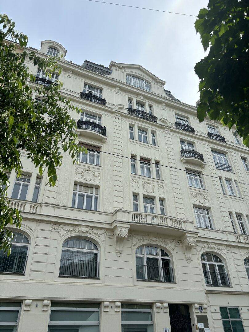 Elegante historische Fassade eines Mehrfamilienhauses mit vielen Fenstern und Balkonen, die den klassischen Stil widerspiegeln.