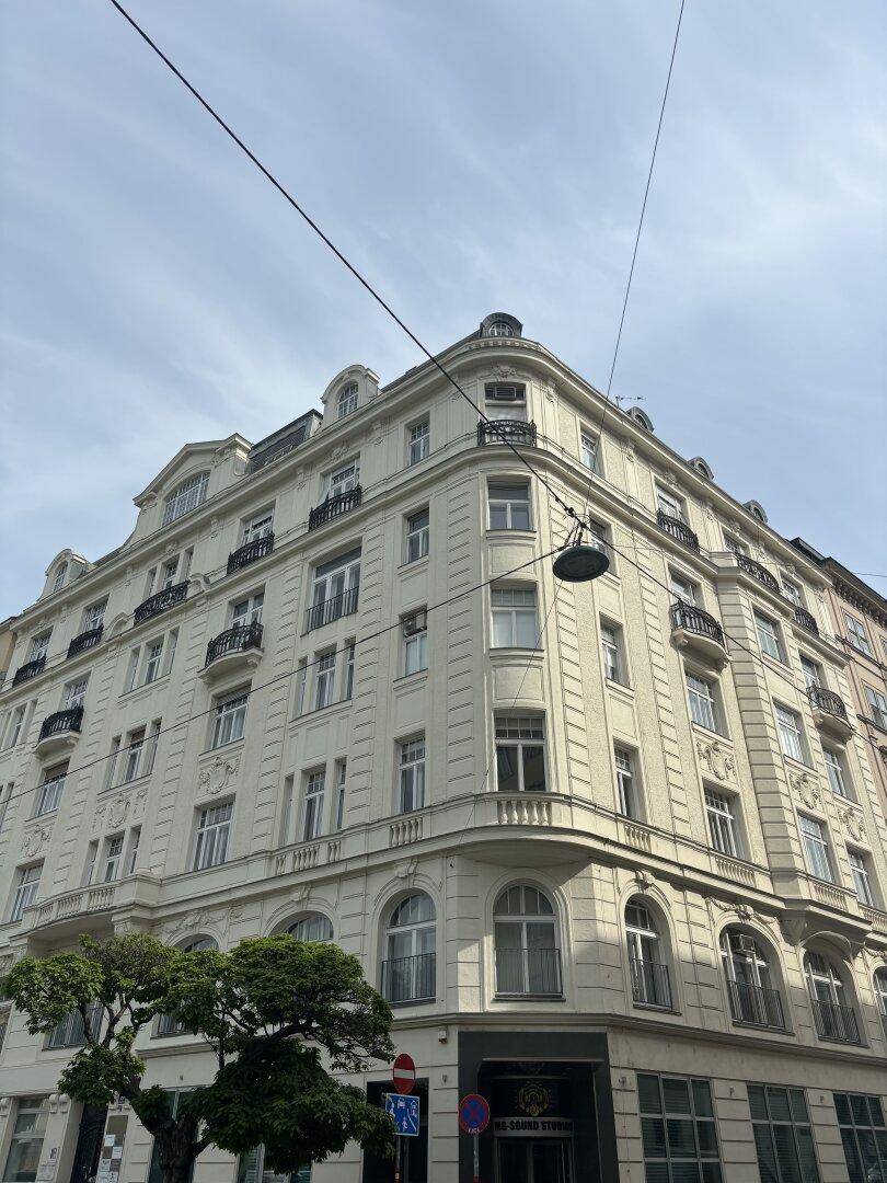 Historisches Eckgebäude mit klassischer Architektur, vielen Fenstern und Balkonen, die das Stadtbild prägen.