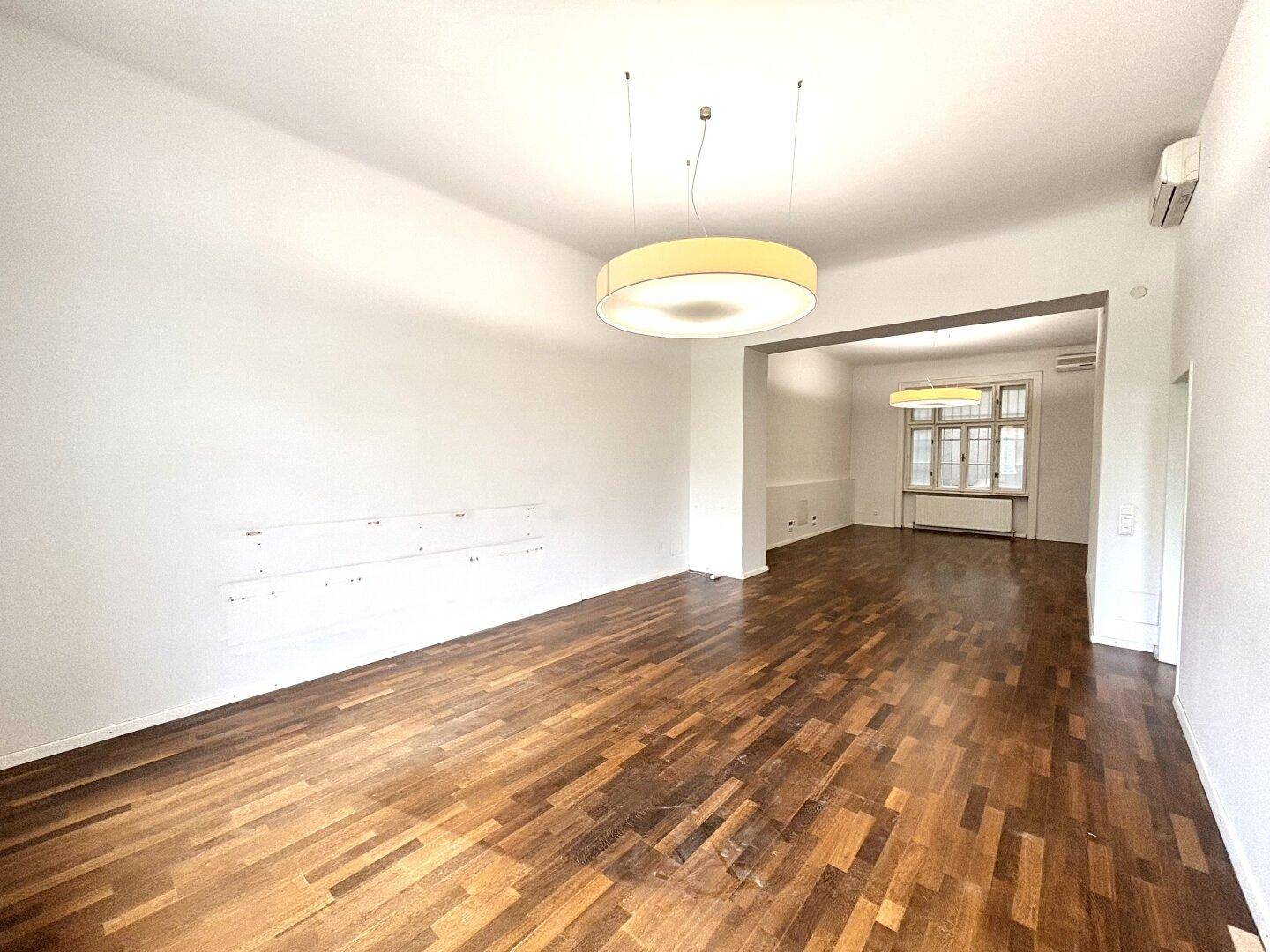 Heller, leerer Raum mit Holzboden und großen Fenstern, bereit zur individuellen Gestaltung und Nutzung.