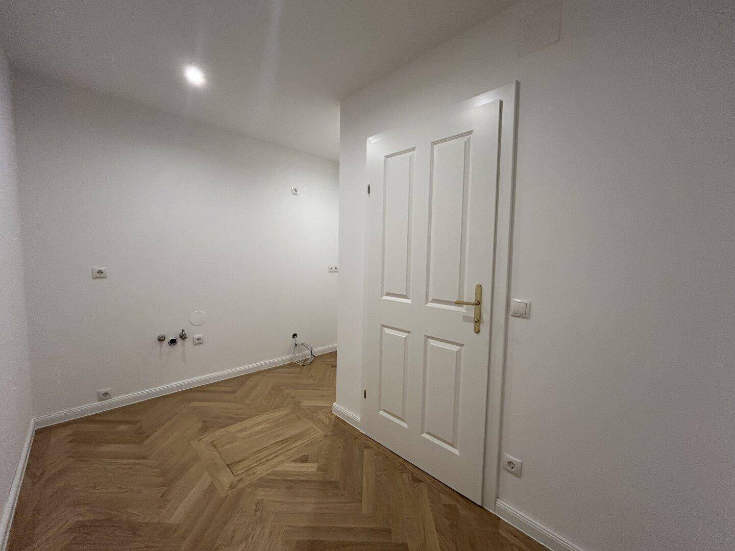 Kleiner Raum mit Fischgrätparkett und einer weißen Tür, der vielseitig genutzt werden kann.