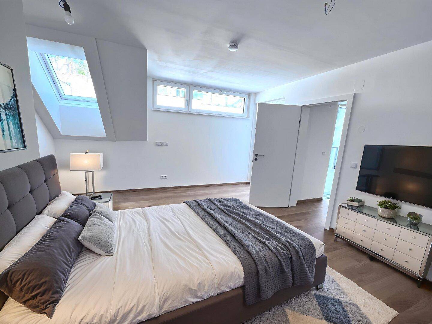 Helles Schlafzimmer mit Holzboden, Dachfenster und viel Tageslicht, bereit zur individuellen Gestaltung.