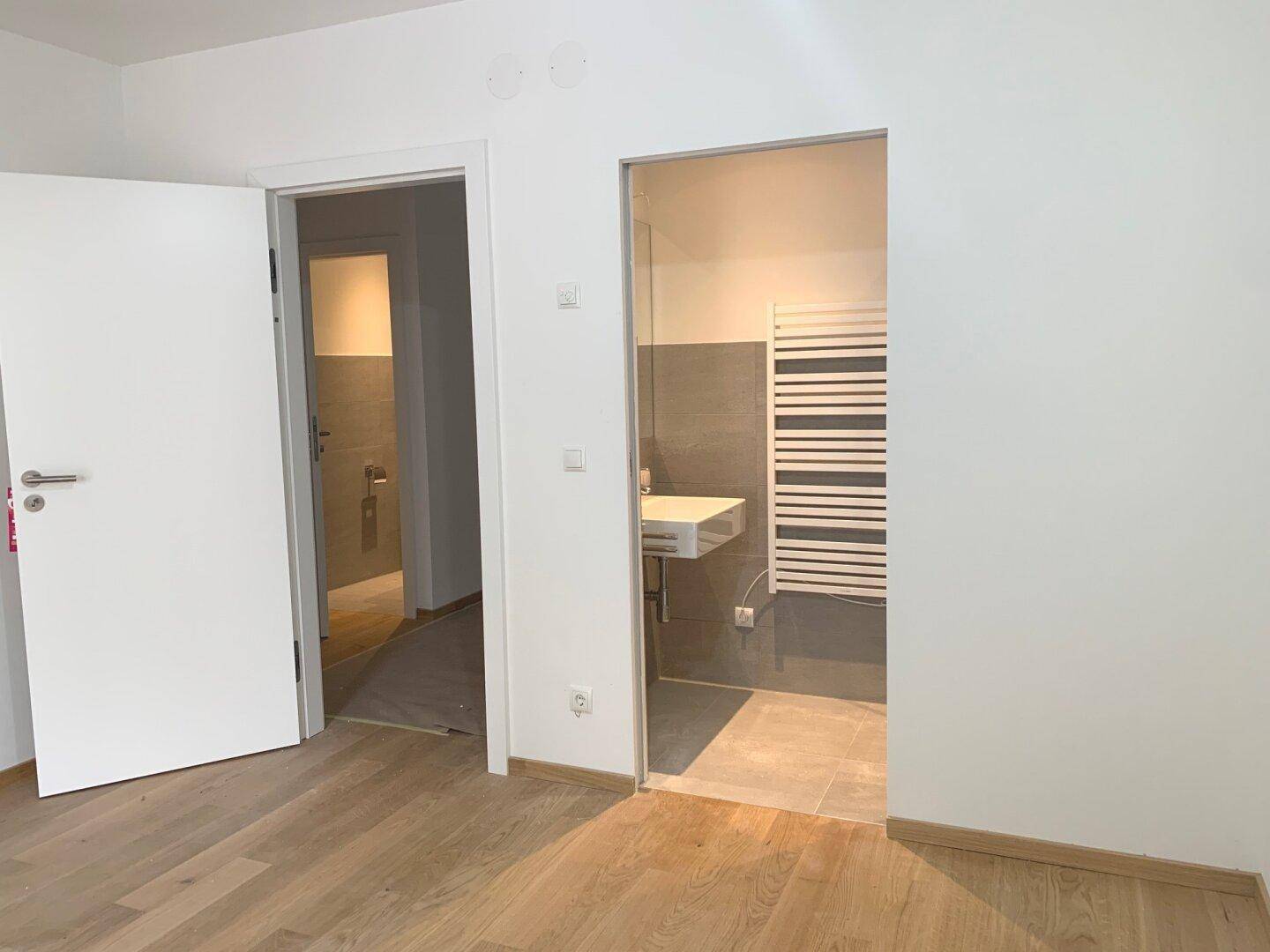 Blick auf einen Flur mit Zugang zu einem Badezimmer und einem separaten Waschbereich.