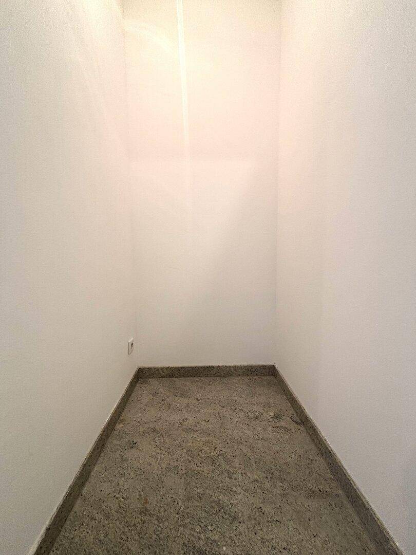 Kleiner Abstellraum mit Fliesenboden und weißen Wänden.