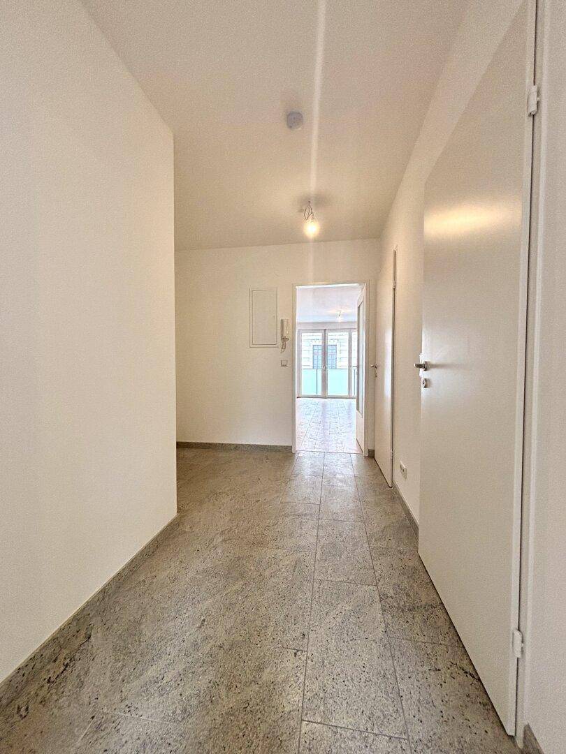 Heller, leerer Flur mit Fliesenboden und Zugang zu weiteren Räumen.