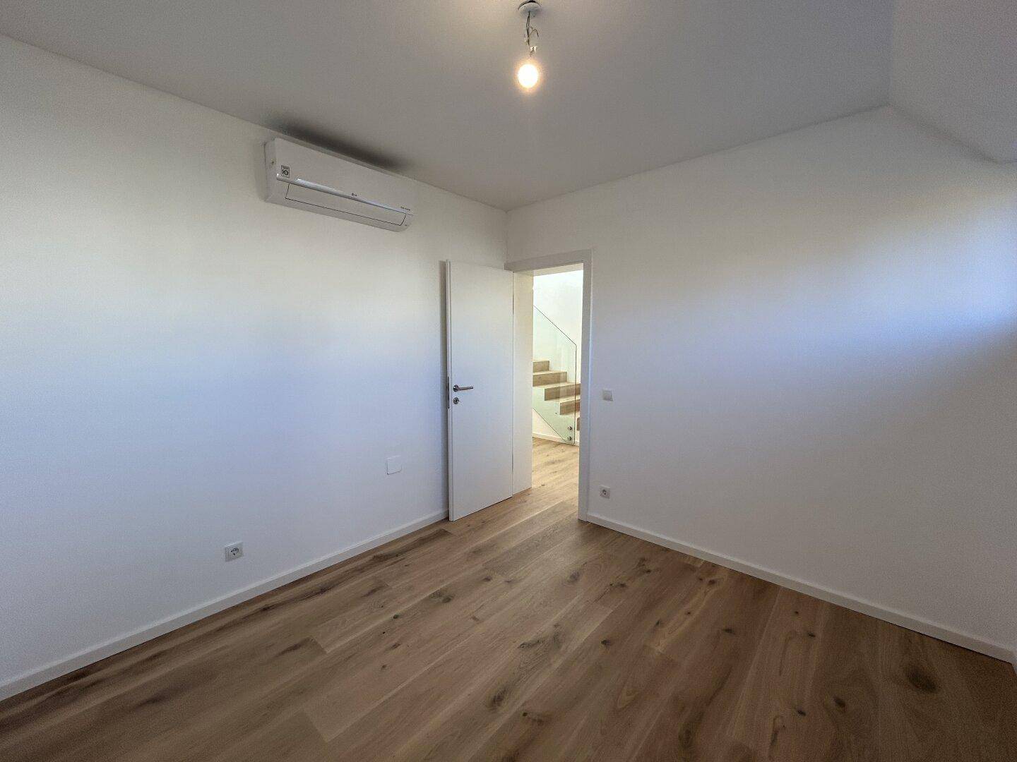 Helles Schlafzimmer mit Holzboden und Klimaanlage, bietet direkten Zugang zum Treppenhaus.