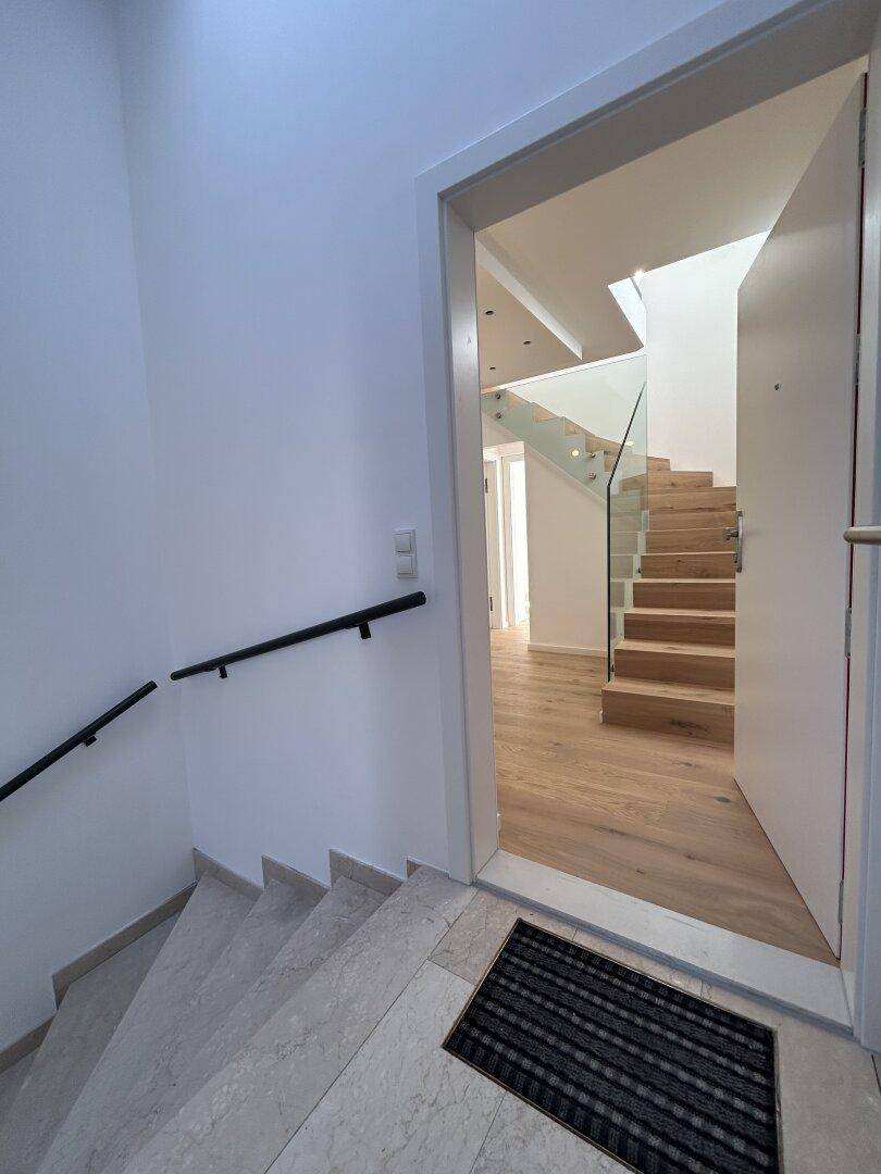 Eingangsbereich mit Marmorboden und Treppe mit Handlauf, führt zu den oberen Etagen.
