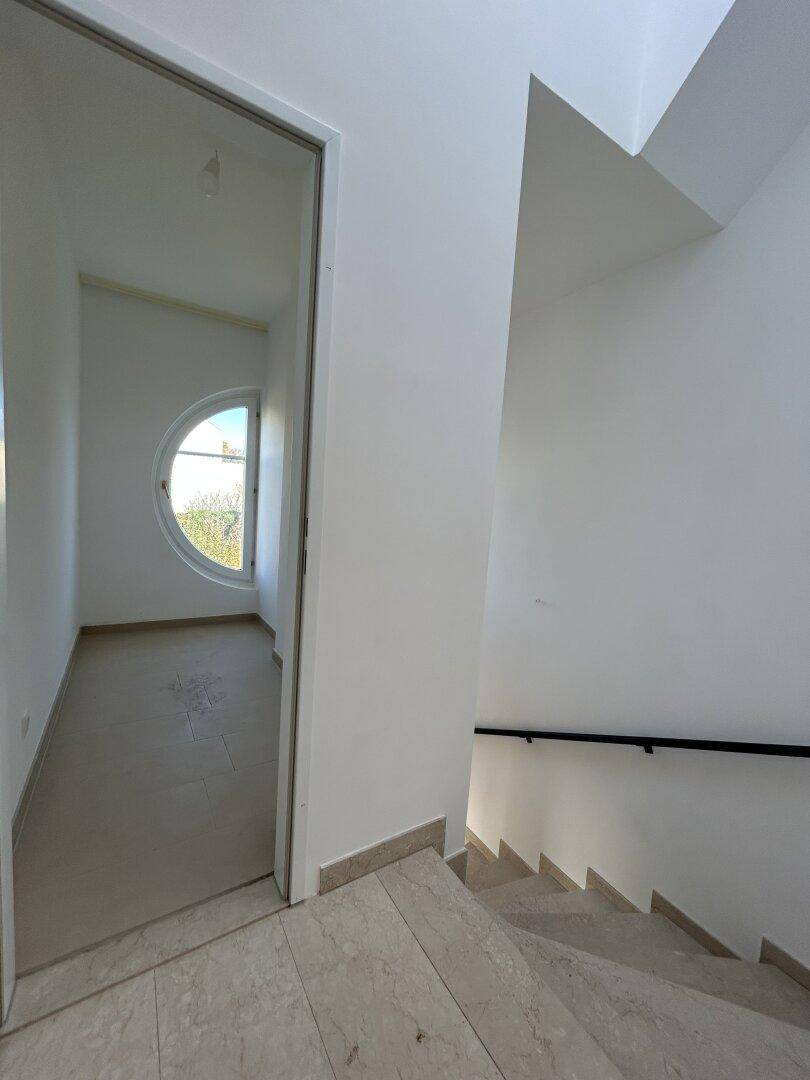 Treppenhaus mit Blick in ein helles Zimmer mit Rundfenster, verbindet die Ebenen des Hauses.