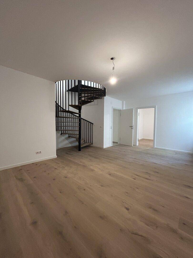 Geräumiger Wohnbereich mit Holzboden und eleganter Wendeltreppe.