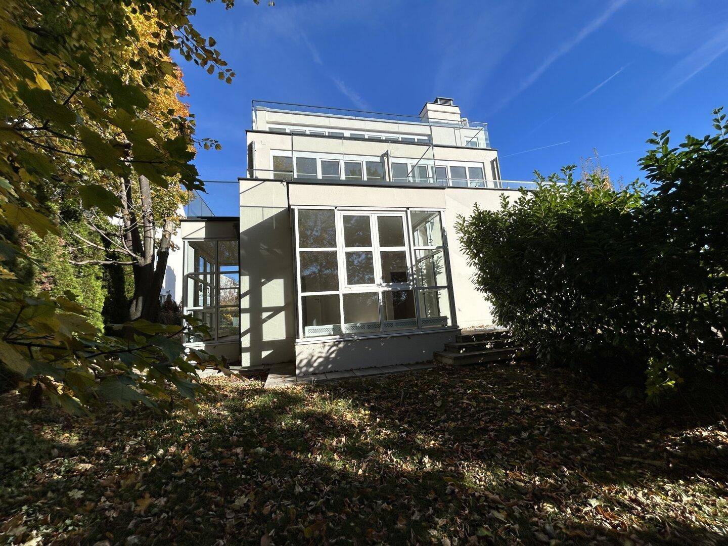 Moderne Gebäudefassade mit großen Fensterfronten und Terrassen, umgeben von Grün.