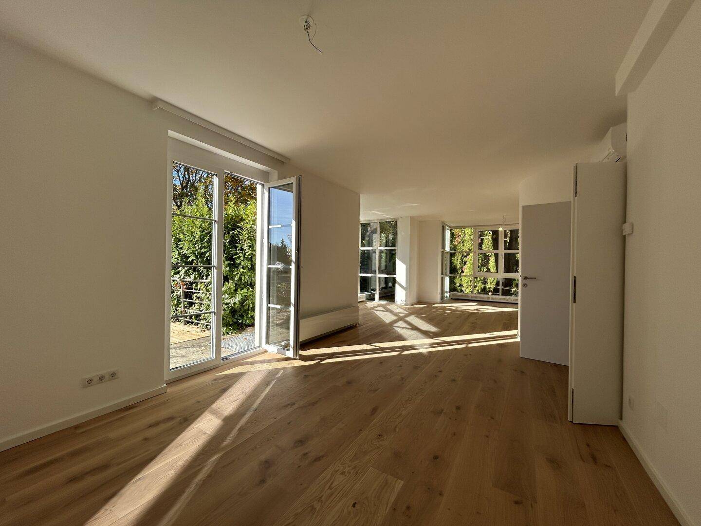 Heller Wohnbereich mit Holzboden, großen Fenstern und Zugang zur Terrasse.