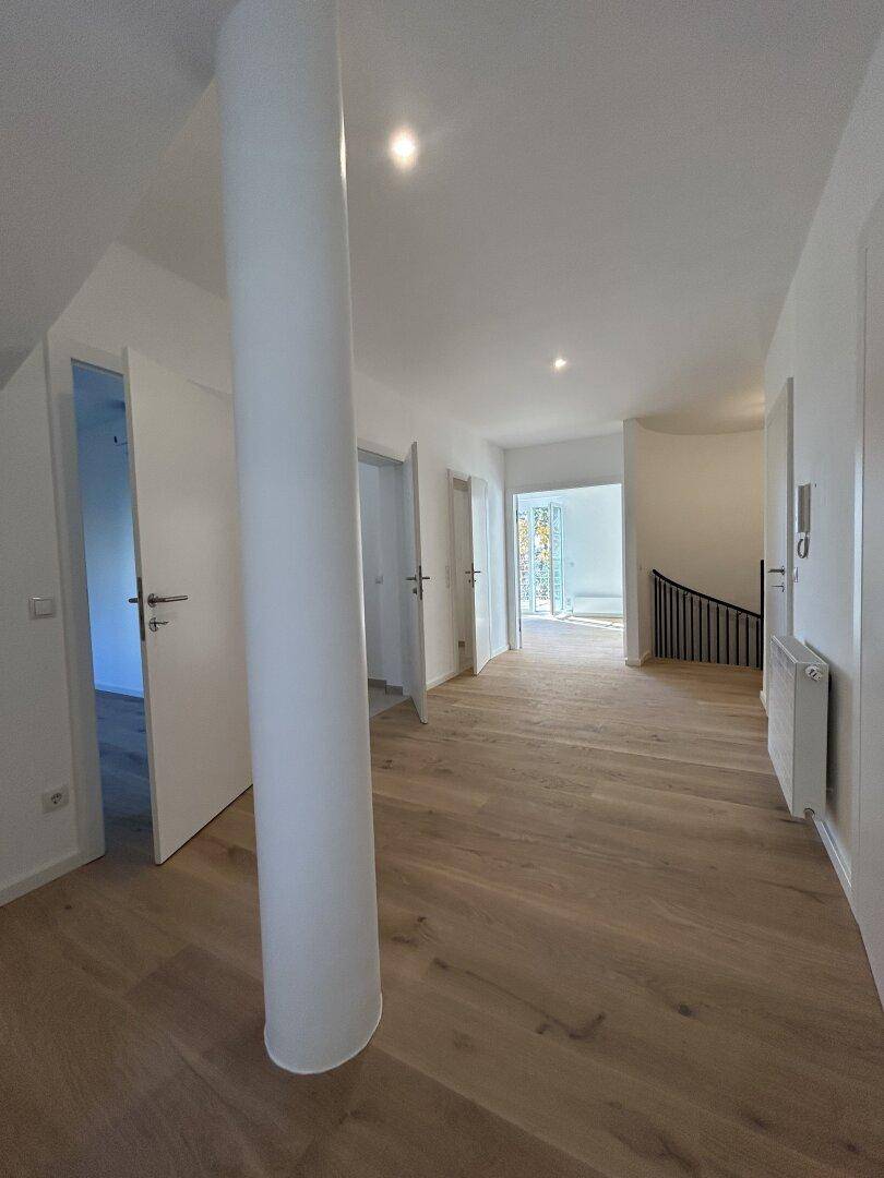 Langer, heller Flur mit Holzboden und mehreren Türen zu den angrenzenden Räumen.