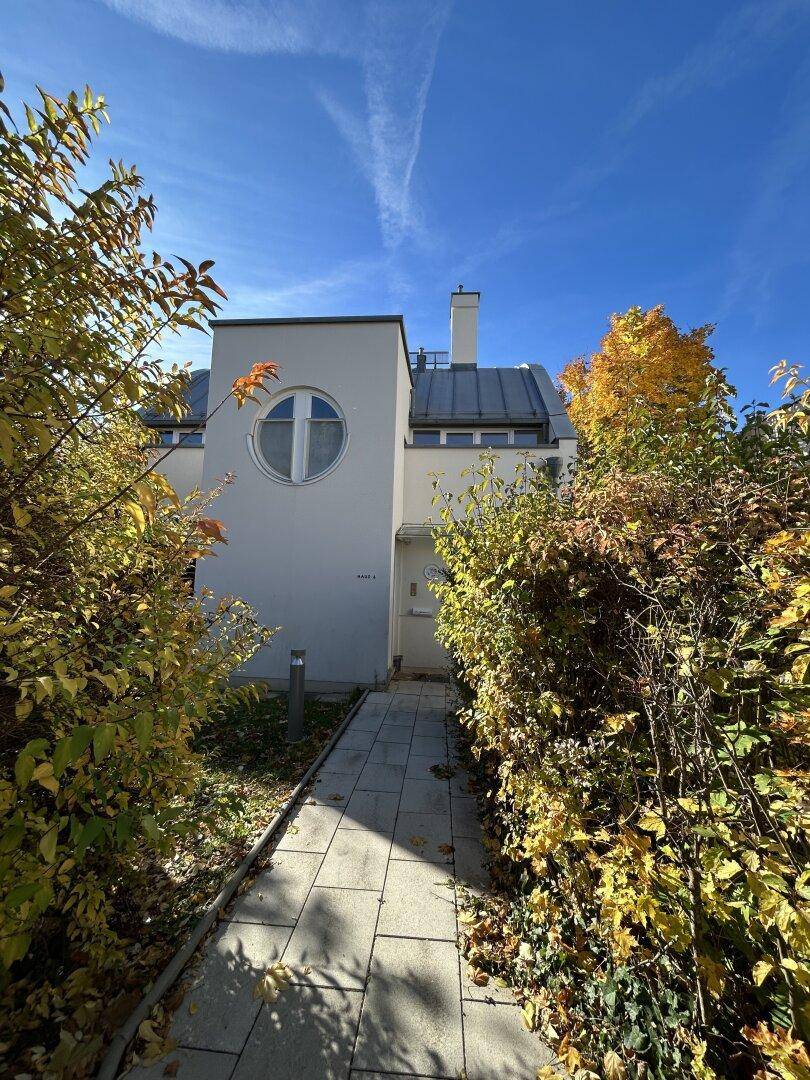 Eingangsbereich des Hauses mit gepflastertem Weg, umgeben von herbstlicher Bepflanzung.
