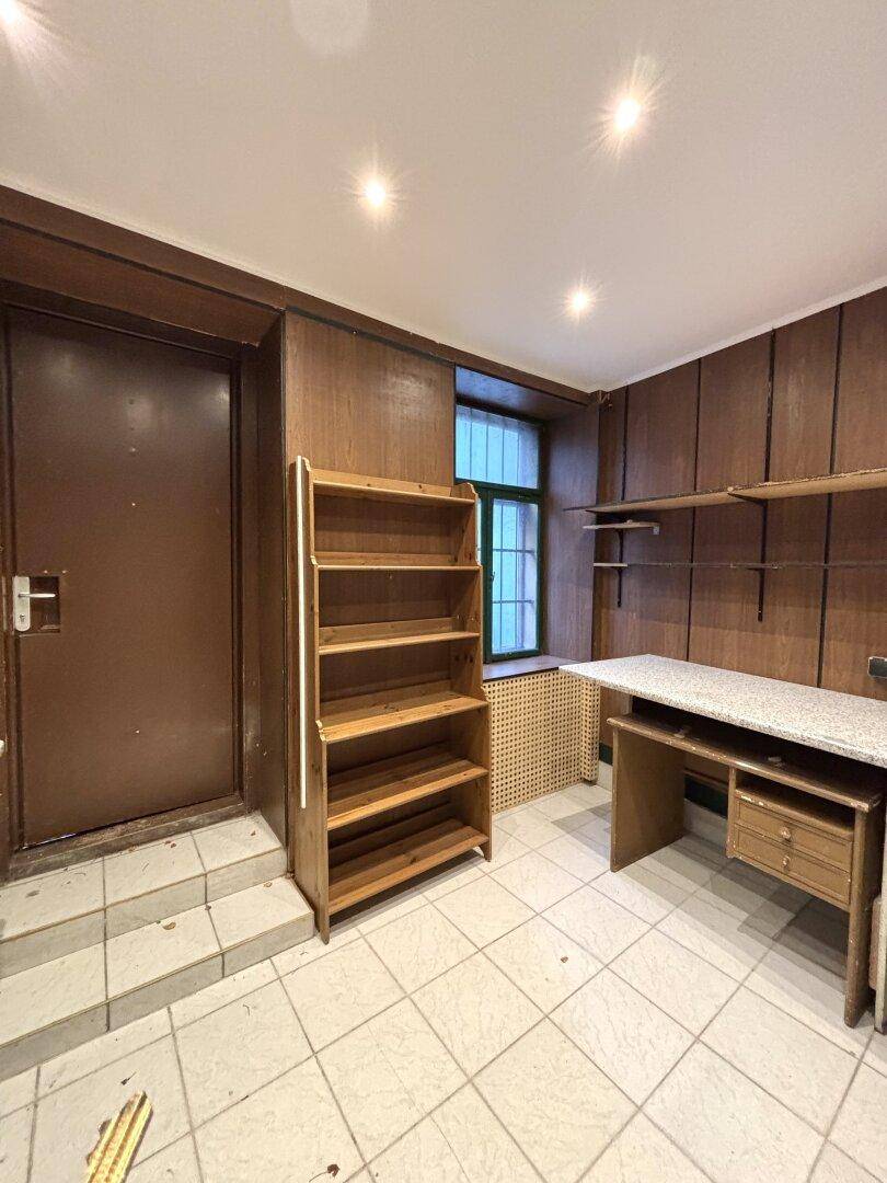 Hinterraum mit Holzregal, Arbeitsplatte und einem Fenster, ideal für Lagerung oder Büro.