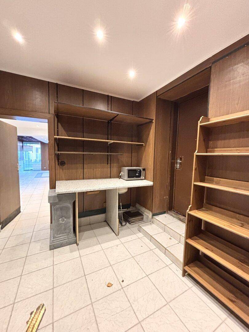Hinterraum mit Arbeitsplatte, Regalen und einer Mikrowelle, ideal für Lagerung oder Büro.