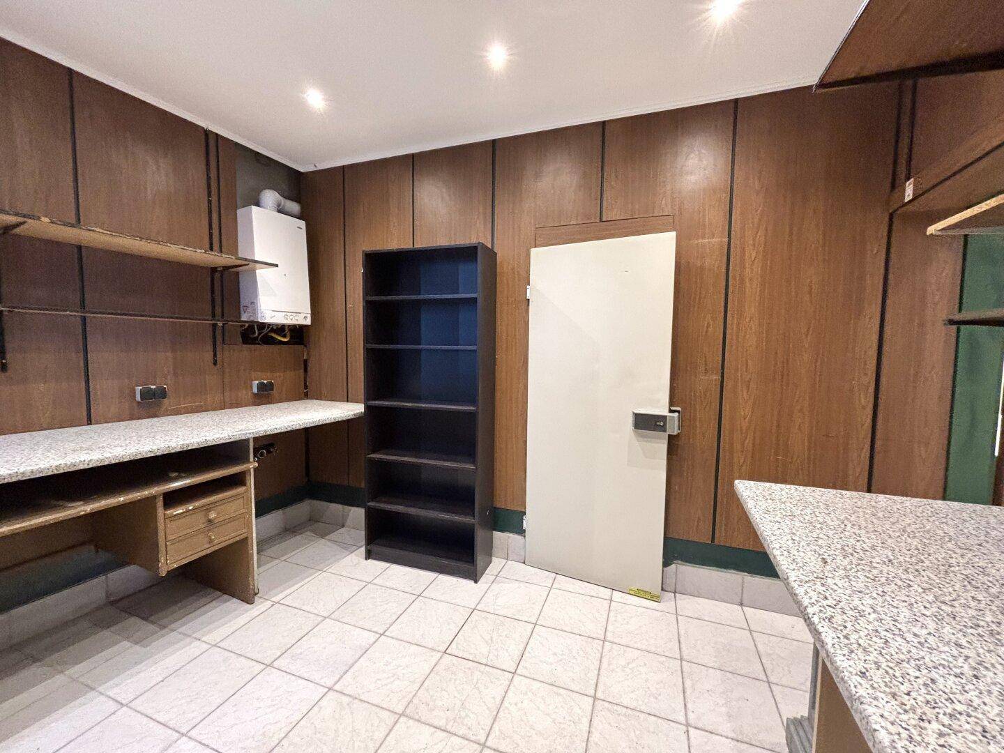 Hinterraum mit Arbeitsplatte, Regalen und einem Wandheizkessel, ideal für Lagerung oder Büro.
