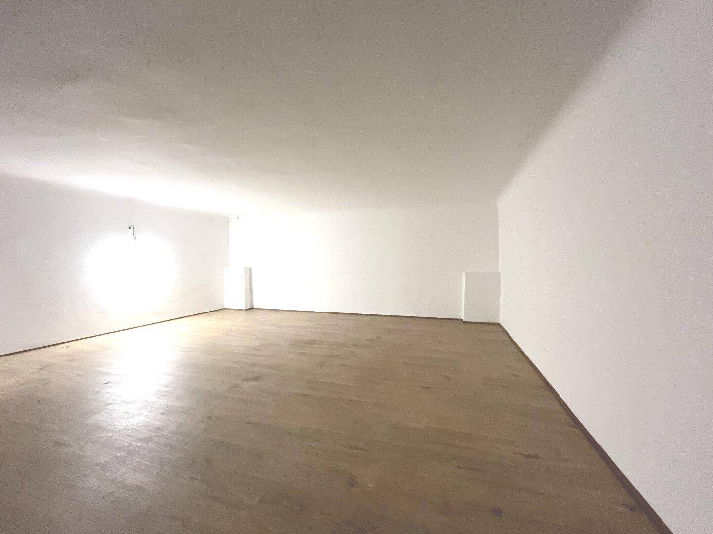 Weitläufiger Raum im Obergeschoss mit Holzboden und viel Tageslicht, ideal für verschiedene Nutzungen.